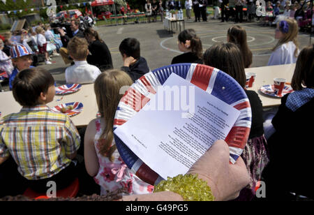 Un insegnante possiede testi scritti dagli alunni e dal personale della Bucklebury Church of England Primary School, per una canzone che stanno cantando per celebrare il matrimonio del Principe William e Kate Middleton durante la loro festa reale di nozze nel campo della scuola. Foto Stock