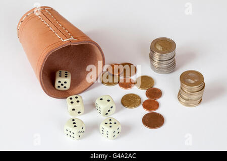 Dadi cup con dadi e impilate le monete in euro, immagine simbolica per il gioco d'azzardo Foto Stock