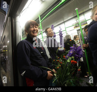 Due donne con fiori acquistati l'ultimo giorno dal RHS Chelsea Flower Show a bordo di un treno alla stazione della metropolitana Sloane Sqaure , nella parte ovest di Londra. Foto Stock