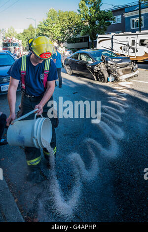 La risposta di emergenza fireman mette giù il materiale per assorbire fuoriuscite di petrolio dopo la testa sulla collisione del veicolo, Vancouver British Columbia, Foto Stock