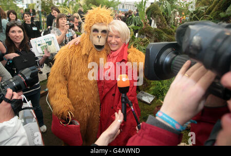 Dame Helen Mirren si pone con un uomo in un costume da scimmia al Borneo Exotics Garden nel Chelsea Flower Show. Foto Stock