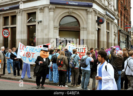 UK Uncut, un gruppo di studenti che protestano contro i tagli alla spesa pubblica per l'NHS, dimostra di fronte a un cordone di polizia fuori da un ramo della NatWest Bank a Camden Town, a nord di Londra, questo pomeriggio. Foto Stock