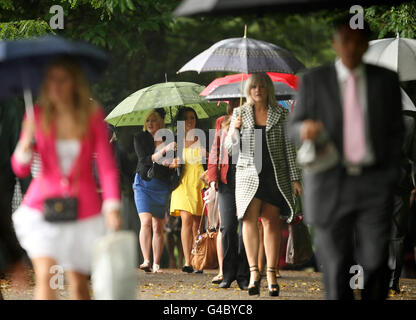 I Racegoers riparano sotto gli ombrelli quando arrivano il terzo giorno del Royal Ascot Meeting all'Ippodromo di Ascot, Berkshire. Foto Stock