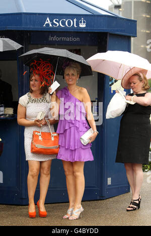 Racegoers rifugio sotto ombrelli il terzo giorno del Royal Ascot Meeting all'Ippodromo di Ascot, Berkshire. Foto Stock