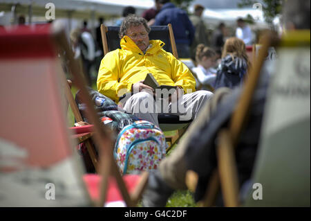 Un uomo legge nel tempo variabile di festa della banca al festival di Hay-on-Wye, Powys, Galles. Foto Stock
