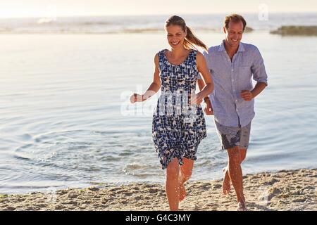 Modello rilasciato. Matura in esecuzione su per la spiaggia, sorridente. Foto Stock