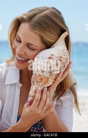 Modello rilasciato. Donna l'ascolto di una conchiglia. Foto Stock