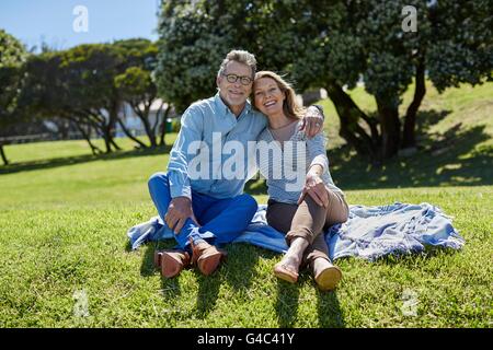 Modello rilasciato. Coppia senior sulla coperta picnic, braccia intorno all'altro. Foto Stock