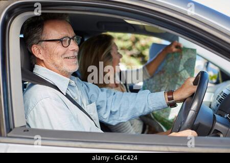 Modello rilasciato. Senior uomo in auto, donna azienda mappa. Foto Stock