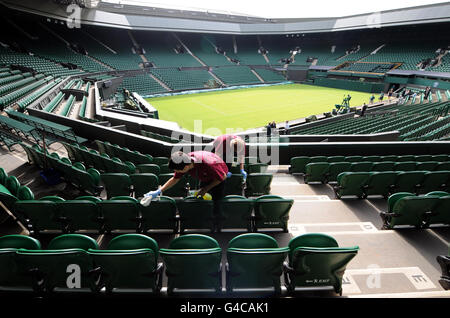 I posti a sedere presso il Centro Court vengono puliti prima del primo giorno dei Campionati di Wimbledon del 2011 presso l'All England Lawn Tennis Club di Wimbledon. Foto Stock