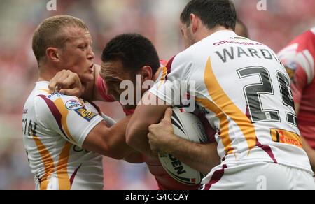 George Carmont (al centro) di Wigan Warriors viene affrontato da Luke Robinson (a sinistra) e Joe Wardle di Huddersfield durante la partita Engage Super League presso il DW Stadium di Wigan. Foto Stock