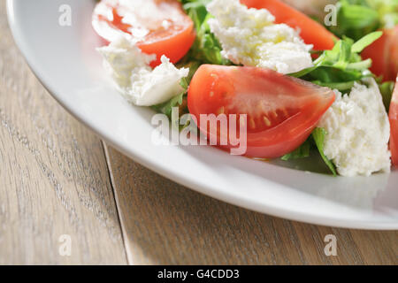 Luce estiva con insalata di pomodori, mozzarella e foglie di rucola Foto Stock