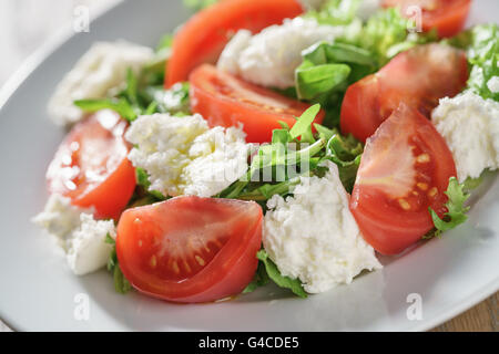 Luce estiva con insalata di pomodori, mozzarella e foglie di rucola Foto Stock