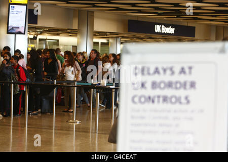 Code al controllo di frontiera nel terminal 5 dell'aeroporto di Heathrow di Londra, dove alcuni membri del personale addetto all'immigrazione e alla dogana si sono Uniti a una giornata di scioperi di insegnanti, funzionari pubblici e altri lavoratori contro i piani del governo per cambiare le pensioni, tagliare posti di lavoro e congelare la retribuzione. Foto Stock