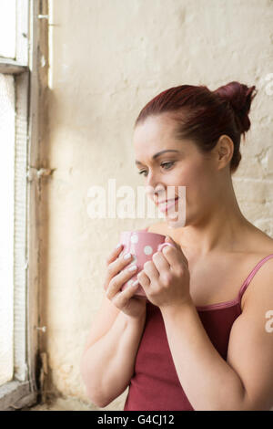 Donna bere il tè da finestra Foto Stock