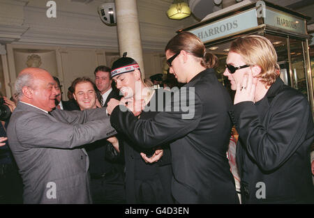 Il boss di Harrods Mohammed al Fayed lega una collana intorno al collo di Shane Lynch, uno dei membri della band Boyzone, che ha lanciato oggi la vendita estiva del negozio Knightsbridge (Mer). Foto di Fiona Hanson/PA Foto Stock