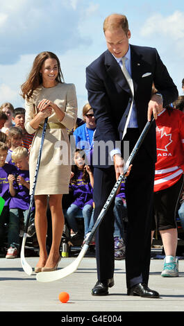 La Duchessa di Cambridge guarda come suo marito, il Duca di Cambridge, prende una pena mentre prova l'hockey di strada, durante una visita alla piazza civica di Somba K'e a Yellowknife, territori del nord-ovest, Canada. Foto Stock
