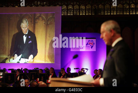 Il Principe del Galles (a destra) viene visualizzato su uno schermo mentre svolge il suo discorso durante la cena del 250° anniversario del Consiglio dei deputati degli ebrei britannici, tenutasi presso la Guildhall nel centro di Londra. Foto Stock