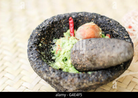 Fotografia di fracassato advocado, guacamole in un tradizionale di pietra molcajete Foto Stock