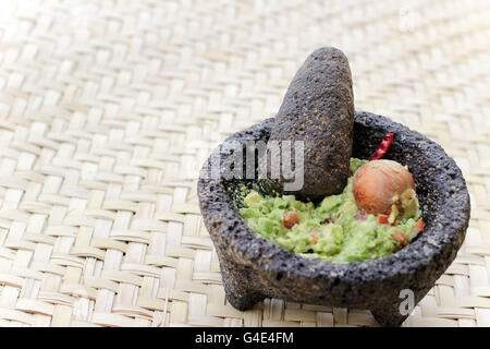 Fotografia di fracassato advocado, guacamole in un tradizionale di pietra molcajete Foto Stock