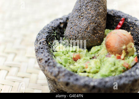 Fotografia di fracassato advocado, guacamole in un tradizionale di pietra molcajete Foto Stock