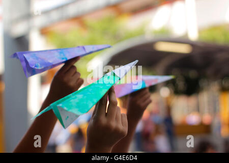 Fotografia di alcuni tipi di carta colorati aeroplani su pronto a volare sui bambini le mani Foto Stock
