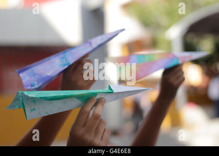 Fotografia di alcuni tipi di carta colorati aeroplani su pronto a volare sui bambini le mani Foto Stock