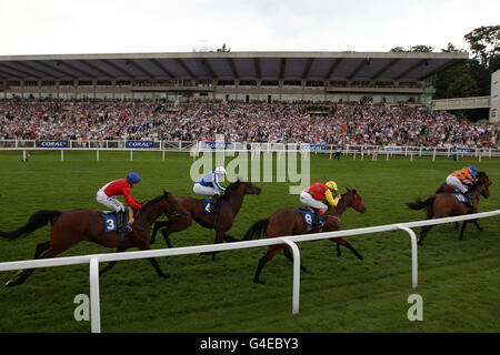 I corridori e i corridori passano davanti alla tribuna piena durante il Vinci di più con coral.co.uk Green Tick handicap Foto Stock