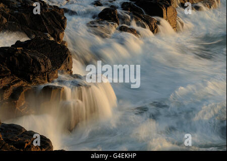 Rottura d'onda sulle rocce della valle culla lunga esposizione creazione di effetto di graduazione sull'acqua Foto Stock