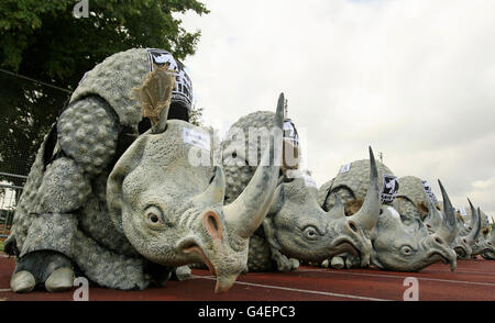 I corridori vestiti con costumi di rinoceronte prendono parte a uno sprint di 100 metri, organizzato da Save the Rhino International, al Mile End Park Stadium, a est di Londra, per evidenziare il lavoro della carità, che conserva popolazioni di rinoceronti in pericolo critico in Africa e Asia. Foto Stock