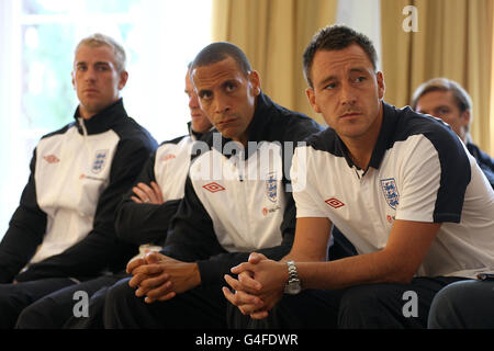 Inghilterra i giocatori (sinistra-destra) Joe Hart, Wayne Rooney, Rio Ferdinand e John Terry (da sinistra a destra) guardano la conferenza stampa mentre il presidente della fa David Bernstein si rivolge ai media sulla cancellazione dell'appuntamento di domani con i Paesi Bassi durante la conferenza stampa al Grove Hotel, Hertfordshire. Foto Stock