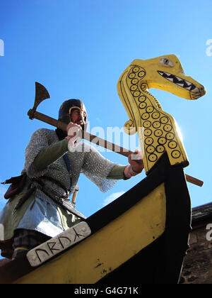 Russell Scott, padre di due sposati di Cheddleton, vicino a Leek, nello Staffordshire, gioca il capo dei vichinghi Rigr sulla prow della longship a Lindisfarne, Northumberland, per lanciare un festival culturale. Foto Stock