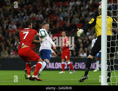 Wayne Rooney in Inghilterra e Joe Ledley in Galles combattono per la palla nella zona durante la partita di qualificazione UEFA Euro 2012 al Wembley Stadium di Londra. Foto Stock