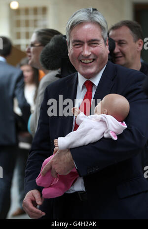 Il leader del partito laburista scozzese Iain Grey tiene un simulatore di bambino nel tentativo di dimostrare che prendere un bambino al lavoro non è fattibile, al Parlamento scozzese, Edimburgo. Foto Stock