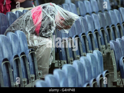 Un ventilatore ripara sotto il suo cappotto dalla pioggia che ha interrotto il gioco alla seconda finale della partita Tra l'Inghilterra e l'Australia al Melbourne Cricket Ground Foto Stock