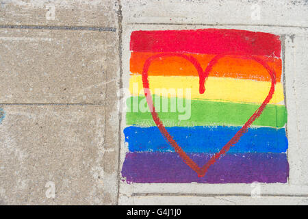 Gay-bandiera arcobaleno e cuore rosso dipinto su un marciapiede Foto Stock