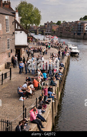 Molte persone bevono e si rilassano nell'affollato pub sul fiume (King's Arms) e nelle barche per il tempo libero sul fiume Ouse - King's Staith, York, North Yorkshire, Inghilterra. Foto Stock