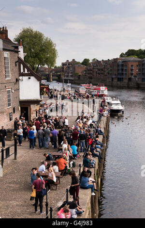 Molte persone bevono e si rilassano nell'affollato pub sul fiume (King's Arms) e nelle barche per il tempo libero sul fiume Ouse - King's Staith, York, North Yorkshire, Inghilterra. Foto Stock
