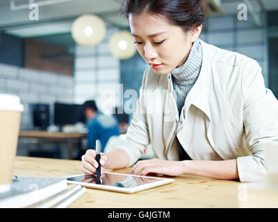 Giovani asiatici designer che lavora in studio utilizzando il disegno digitale della penna e della tavoletta. Foto Stock