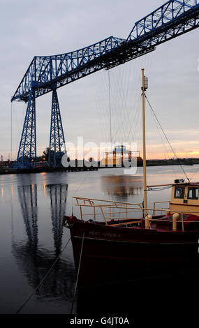 Il sole sorge dietro il ponte trasportatore a Middlesbrough, Teeside, che festeggia il suo 100° compleanno questo fine settimana. Foto Stock