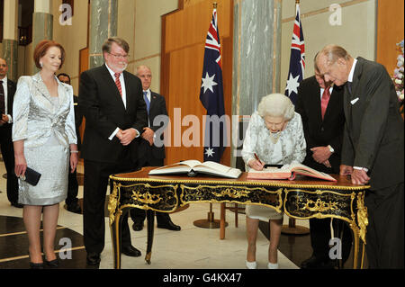 La regina Elisabetta II firma il libro dei visitatori seguito dal duca di Edimburgo e dal primo ministro australiano Julia Gillard dopo un ricevimento nel palazzo del governo nella capitale australiana di Canberra. Foto Stock