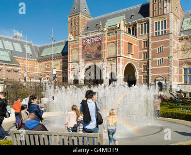 Le persone si raccolgono al di fuori di Amsterdam il RIjksmuseum per giocare in un giardino fontana in una bella giornata di primavera. Foto Stock