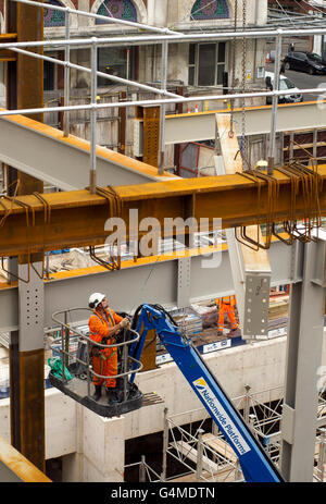 Operaio edile in un paranco installazione di travi al biglietto orientale sito Hall di Crossrail, stazione di Farringdon, Londra Foto Stock