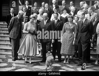 L'attenzione della Regina viene rubata dal poodle, animale domestico del suo accompagnatore, che si è inanguito nella foto dopo pranzo durante la visita reale alla casa del Principe ereditario Olav a Skaugum, vicino Oslo. Sul davanti, da sinistra a destra, sono: Re Haakon di Norvegia; principessa Ragnhild, signora Lorentzen; la Regina; principe ereditario Olav; Il Principe Harald; la Principessa Astrid e il Duca di Edimburgo. Foto Stock