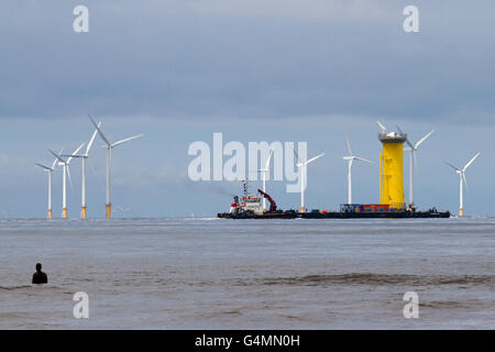 La spedizione di lasciare il fiume Mersey, attraversando il Burbo, centrali eoliche a Crosby, Merseyside, Regno Unito. Cammell Laird è usato come la porta di base per la costruzione del Gwynt y Môr wind farm componenti n sul mare irlandese. La zona del porto si estende per circa 14 ettari 32 ettari e comprende una banchina di 230 metri. È da qui che le fondamenta di 160 turbine eoliche sono preassemblati, caricato e spedito al 576 megawatt di energia eolica in Liverpool Bay posizionato intorno 18 chilometri al largo della costa del Galles. Foto Stock