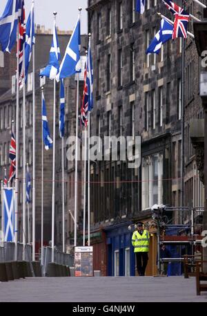 Un poliziotto pattuglia il Royal Mile di Edimburgo, prima della processione e dell'apertura ufficiale della Regina del Parlamento scozzese. Foto Stock