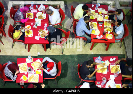 Il Cairo, Egitto. Il 18 giugno, 2016. Le persone si radunano per avere l'Iftar pasto, il pasto consumato dai musulmani per rompere il loro veloce dopo il tramonto ogni giorno durante il mese sacro del Ramadan, nel 'Syrian Street' del 6 ottobre la città, l'Egitto, il 18 giugno 2016. © Ahmed Gomaa/Xinhua/Alamy Live News Foto Stock