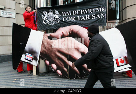 I manifestanti di Greenpeace bloccano l'ingresso al Dipartimento per i trasporti di Horseferry Road, Londra, dopo aver dichiarato che i documenti rilasciati hanno dimostrato come i funzionari del dipartimento dei trasporti stiano lavorando contro una proposta europea chiave che avrebbe bloccato il petrolio di sabbie bituminose, il petrolio più sporco del mondo, Dalla fine in pompe di benzina in tutta Europa. Foto Stock