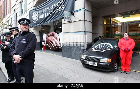 I manifestanti di Greenpeace usano un'auto per bloccare l'ingresso principale del Dipartimento per i trasporti di Horseferry Road, Londra, dopo aver chiesto che i documenti rilasciati mostrassero come i funzionari del dipartimento dei trasporti stiano lavorando contro una proposta europea chiave che avrebbe bloccato il petrolio di sabbie bituminose, il petrolio più sporco del mondo, Dalla fine in pompe di benzina in tutta Europa. Foto Stock