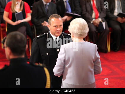 Assistente capo Constable della polizia dello Yorkshire occidentale John Parkinson è reso un OBE dalla Regina durante una cerimonia di investitura a Buckingham Palace, Londra. Foto Stock